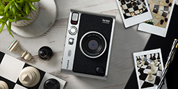 [photo]Fujifilm instax mini Evo with sample prints and chess board on a table